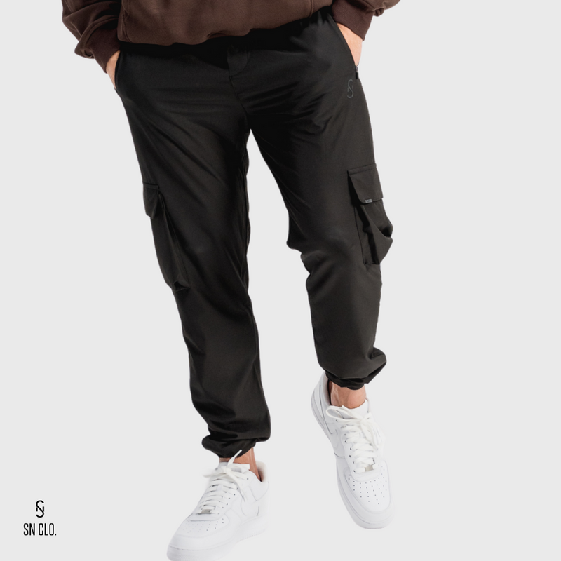 Man wearing black SN Clo cargo pants and white sneakers on a light grey background