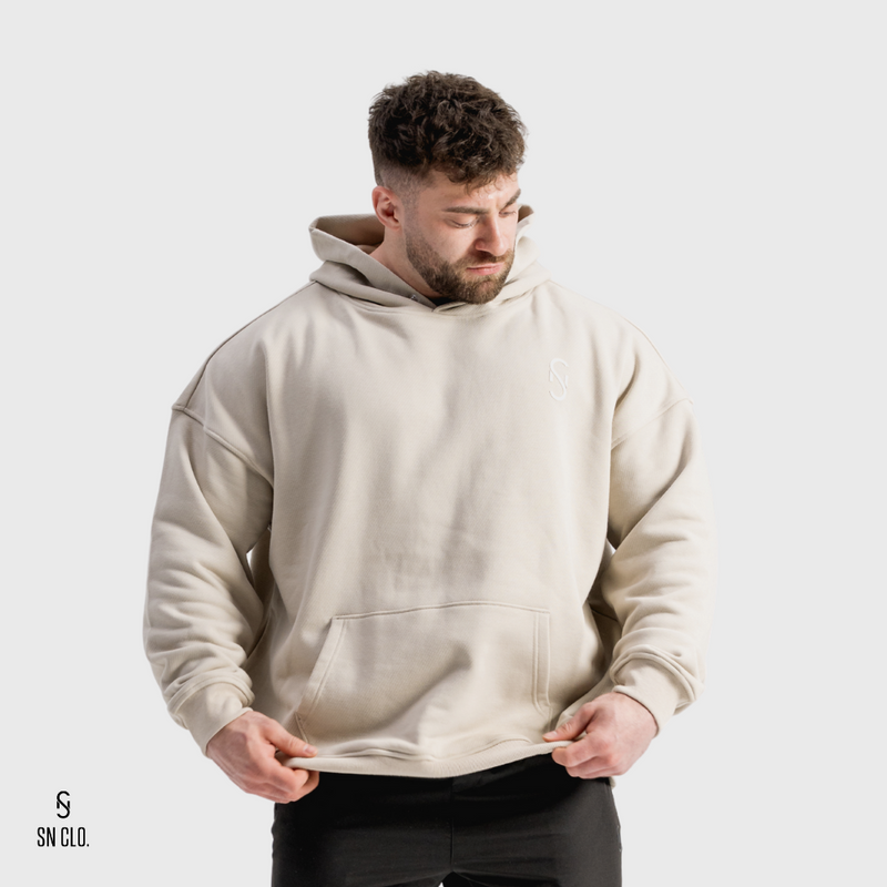 Man wearing a beige hoody with an SN Clo logo on a grey background