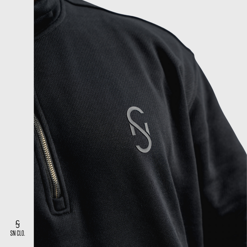 Person wearing a black SN Clo 3/4 zip sweatshirt with SN Clo logo on the front against a white background