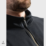 Close-up of a person wearing a black 3/4 zip sweatshirt with a rubber zipper, brand 'SN CLO.' visible.