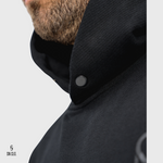 Close-up of a SN Clo. black hooded garment with a button on a white background