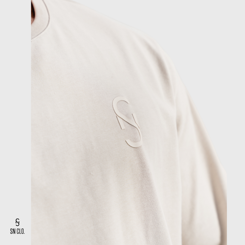 Beige SN Clo. tee with logo on the front on a white background