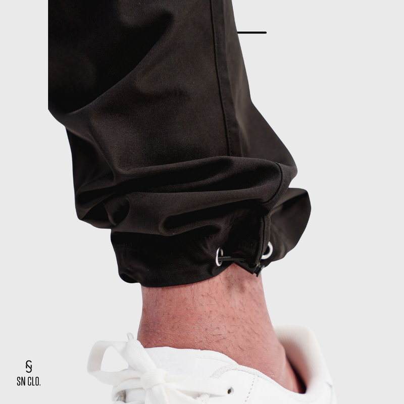 Close-up of a person wearing black pants with a white background