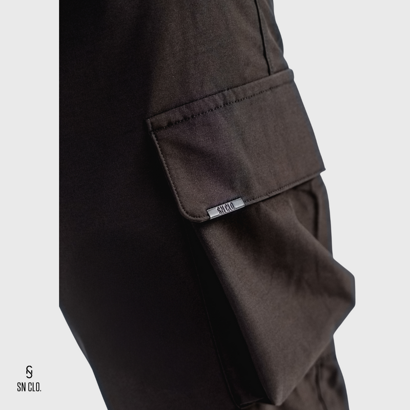 Black SN Clo. pants with a visible brand label on pocket on a light grey background