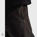 Close-up of a SN Clo. black cargos with a zipper on the pocket and logo on a light grey background