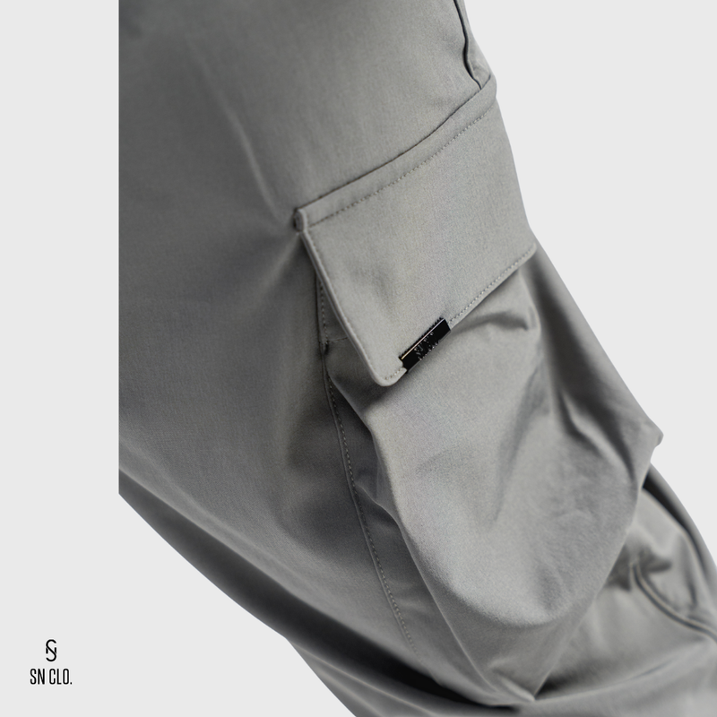 Grey SN Clo. pants with a visible brand label on pocket on a light grey background