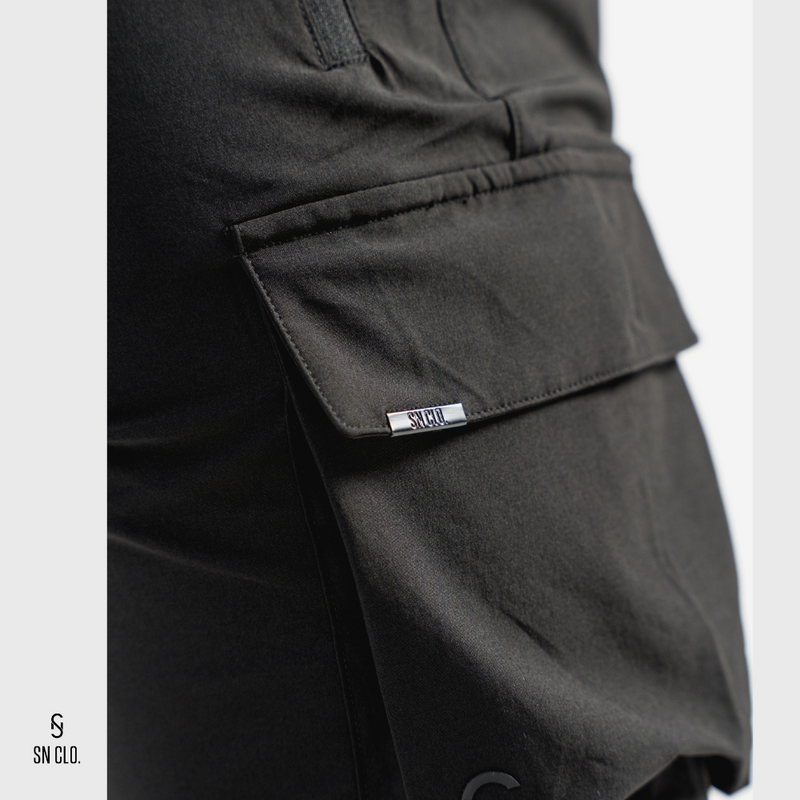Black SN Clo. cargo shorts with a visible brand label on pocket on a light grey background