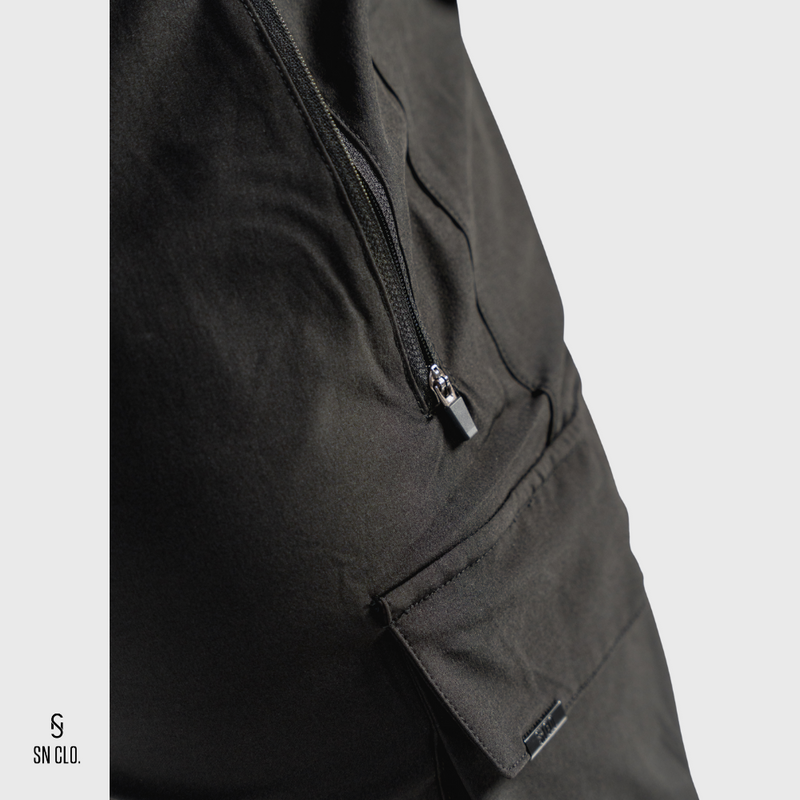 Close-up of SN Clo. black cargo shorts with a zipper on a light grey background