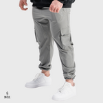 Man wearing grey SN Clo cargo pants and white sneakers on a light grey background