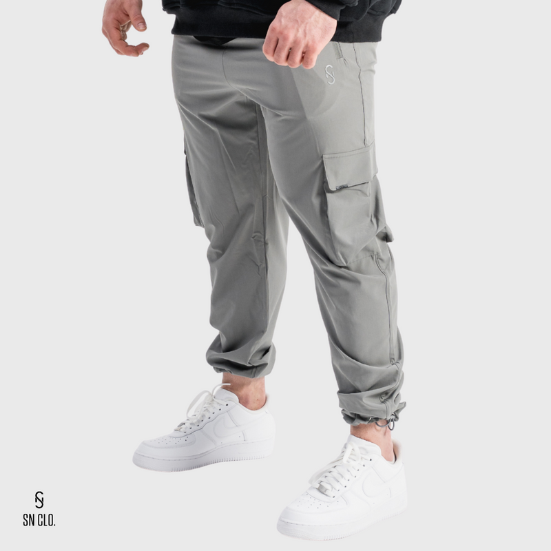 Man wearing grey SN Clo cargo pants and white sneakers on a light grey background