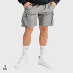 Man wearing grey SN Clo cargo shorts and white sneakers on a light grey background
